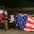 A homeless man is a criminal for sleeping under an American Flag blanket on a park bench.