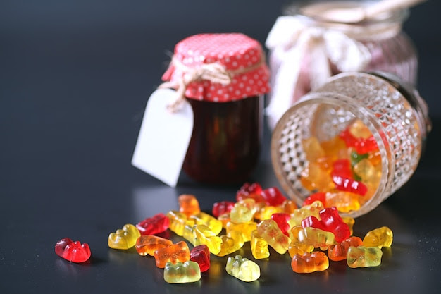 Marmalade in a vase on table. sweets in a bowl on a black background. multicolored jelly sweets for children.