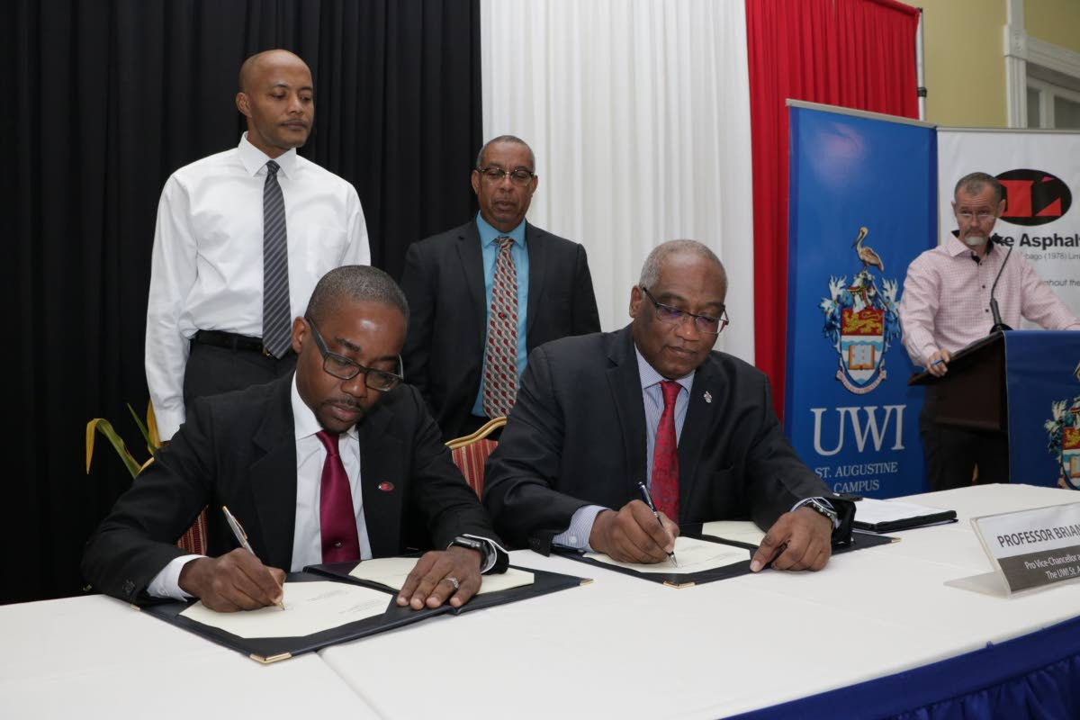 SIGNED: CEO of Lake Asphalt TT Ltd Roger Wiggins, left, and The UWI St Augustine campus principal Prof Brian Copeland sign the licence agreement while Dr Richard Fairman, standing at left, StephenMc Clashie and Julian Henry, far right, look on. PHOTO COURTESY THE UWI