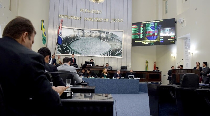 Imagem mostra sala da Assembleia Legislativa de Alagoas, com deputados sentados em mesas, de costas para a câmera