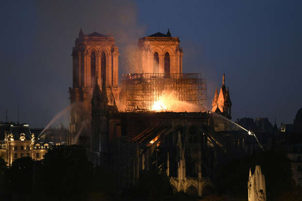 Slide 10 of 31: Smoke and flames rise during a fire at the landmark Notre-Dame Cathedral in central Paris on April 15, 2019, potentially involving renovation works being carried out at the site, the fire service said. - A major fire broke out at the landmark Notre-Dame Cathedral in central Paris sending flames and huge clouds of grey smoke billowing into the sky, the fire service said. The flames and smoke plumed from the spire and roof of the gothic cathedral, visited by millions of people a year, where renovations are currently underway. (Photo by Bertrand GUAY / AFP)        (Photo credit should read BERTRAND GUAY/AFP/Getty Images)