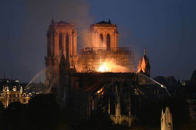 Slide 10 of 31: Smoke and flames rise during a fire at the landmark Notre-Dame Cathedral in central Paris on April 15, 2019, potentially involving renovation works being carried out at the site, the fire service said. - A major fire broke out at the landmark Notre-Dame Cathedral in central Paris sending flames and huge clouds of grey smoke billowing into the sky, the fire service said. The flames and smoke plumed from the spire and roof of the gothic cathedral, visited by millions of people a year, where renovations are currently underway. (Photo by Bertrand GUAY / AFP) (Photo credit should read BERTRAND GUAY/AFP/Getty Images)