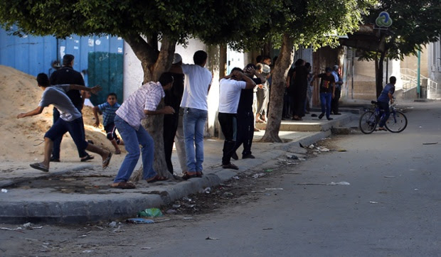 Palestinians take cover in a street in Gaza City, during an Israeli air strike.