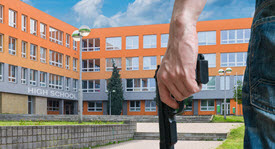 man with a gun standing outside a high school