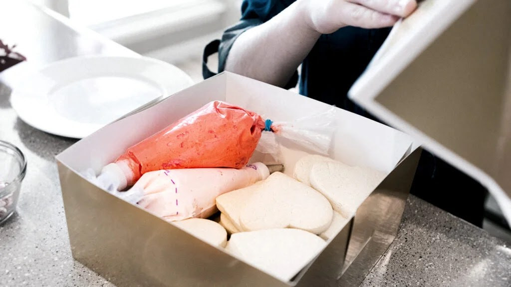 A container of frosting, one of which is red.