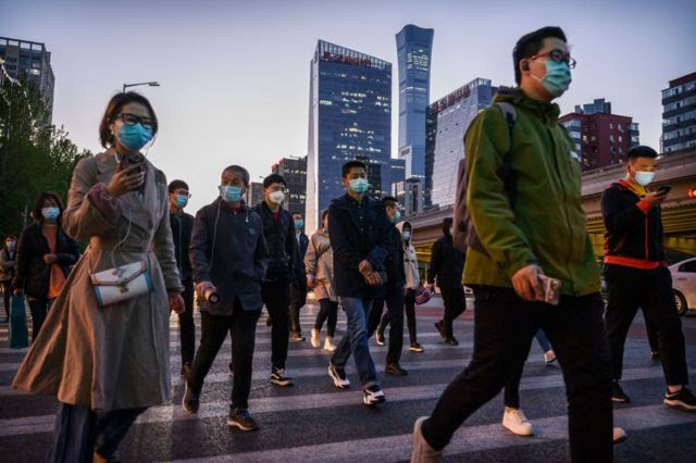 Trabalhadores cruzam uma rua de Pequim durante a hora do rush