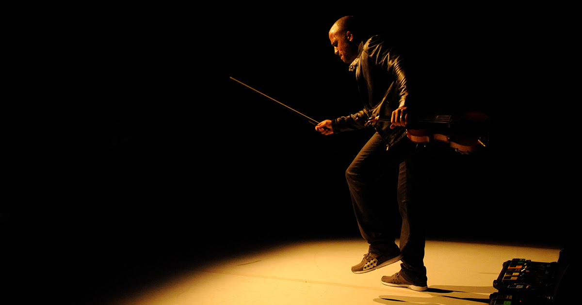 Daniel Bernard Roumain on stage under a spotlight