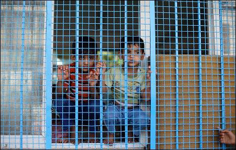 Dos muchachos palestinos, que huyeron la casa de su familia antes de la ofensiva terrestre israelí, miran por la ventana del aula de la escuela Naciones Unidas-run en Rafah, en el sur de la Franja de Gaza.
