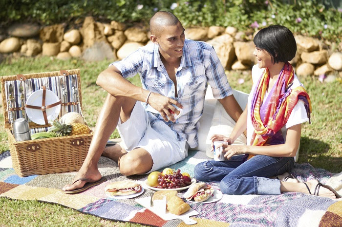 Photo of couple enjoying food during a picnic.
