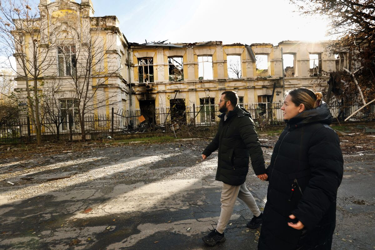 A Ukrainian couple walks past a building that had been used by Russian troops