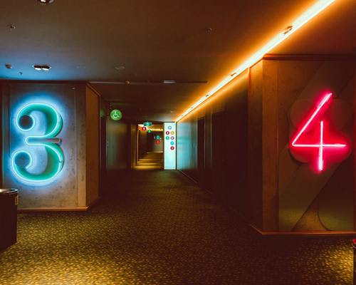 neon numbers 3 and 4 in a hallway