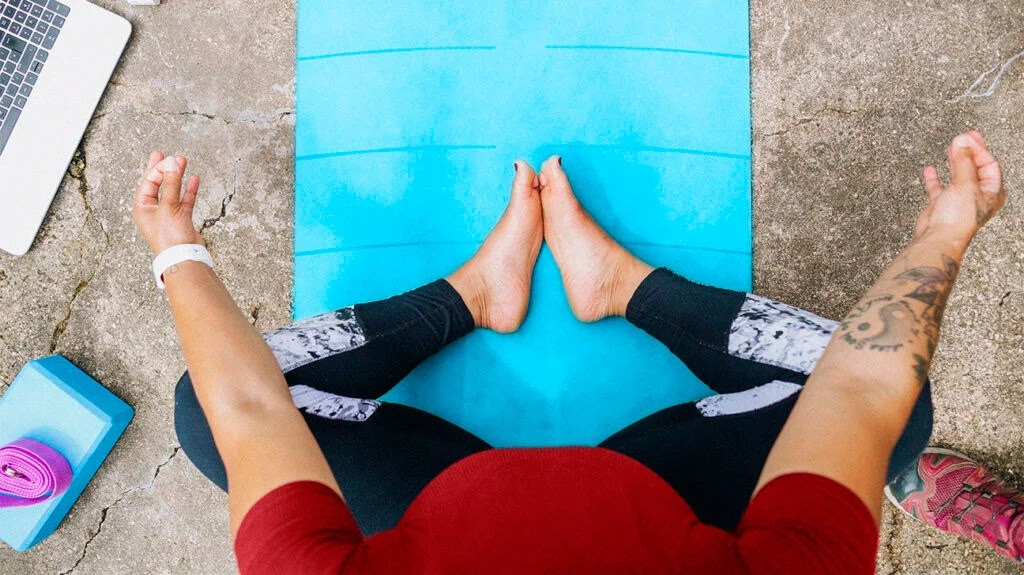 A person sitting on a yoga mat who may have back pain as a result of ankylosing spondylitis.