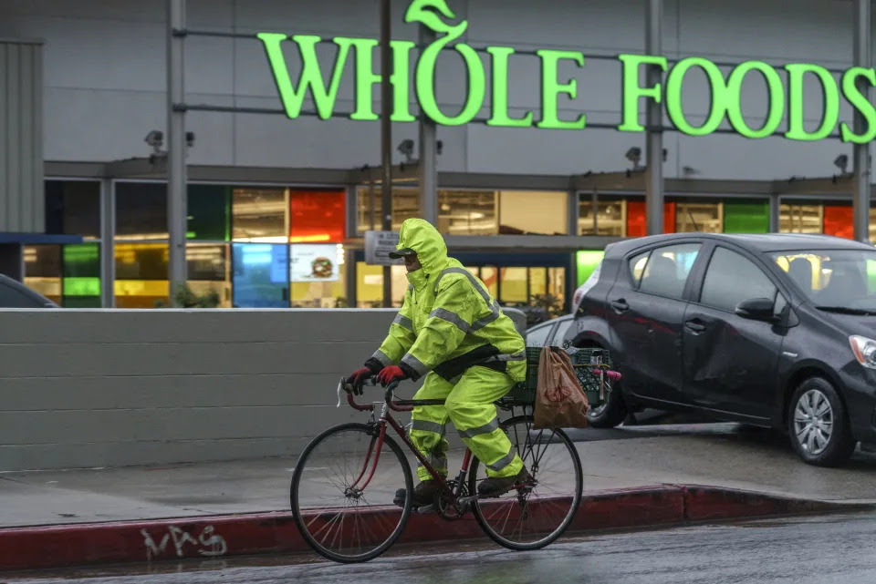 A cyclist wears rain gear in Los Angeles Saturday, Jan. 14, 2023. Storm-battered California got more wind, rain and snow on Saturday, raising flooding concerns, causing power outages and making travel dangerous. (AP Photo/Damian Dovarganes)