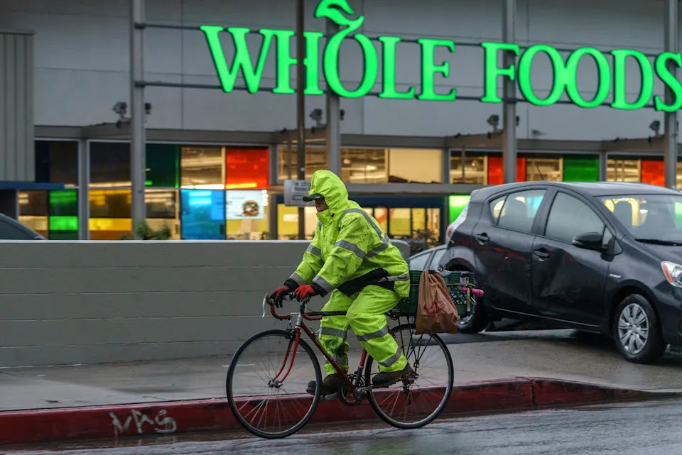 A cyclist wears rain gear in Los Angeles Saturday, Jan. 14, 2023. Storm-battered California got more wind, rain and snow on Saturday, raising flooding concerns, causing power outages and making travel dangerous. (AP Photo/Damian Dovarganes)