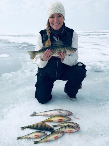 Woman holds the fish she caught on a frozen lake