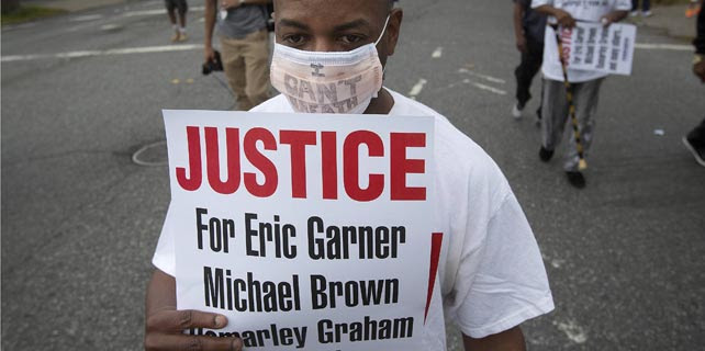 Uno de los participantes en la manifestación de este sábado contra la brutalidad policial y por la muerte de Eric Garner en Staten Island, Nueva York. REUTERS/Carlo Allegri