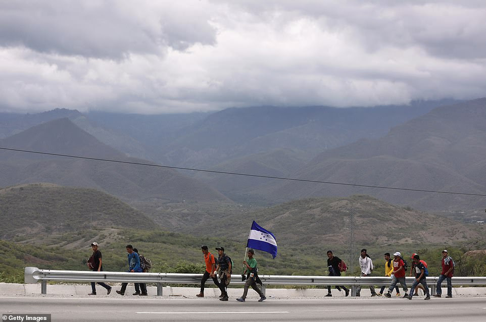 Immigrants, part of a migrant caravan, carry a Honduran flag on