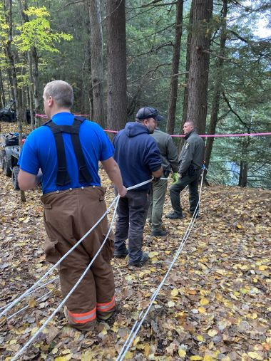 emergency response teams in woods holding ropes during rescue