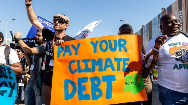 Ativistas fazem prostesto durante a COP27 e cobram que países 'paguem a dívida climática', como escrito e inglês no cartaz