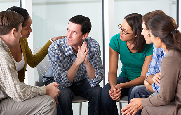 A man being comforted by a support group.