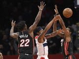 Washington Wizards guard Bradley Beal, center, passes the ball between Miami Heat forward Jimmy Butler (22) and forward Derrick Jones Jr. (5) during the first half of an NBA basketball game, Sunday, March 8, 2020, in Washington. (AP Photo/Nick Wass)