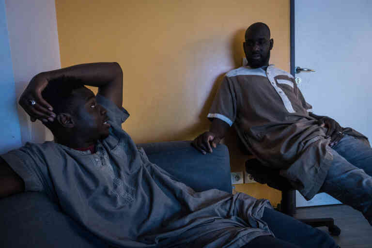 Moussa (à gauche) et Diaguely (droite) se reposent devant la télé avant d'aller travailler.
