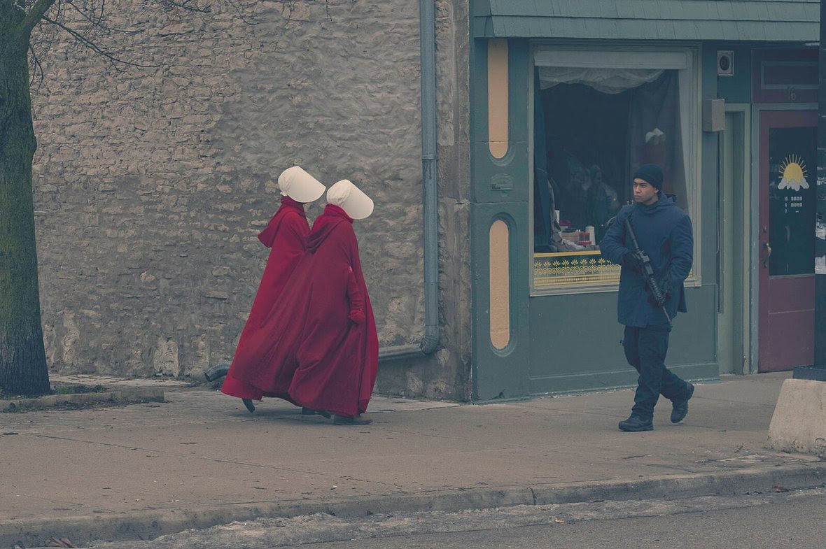 handmaids walking past man