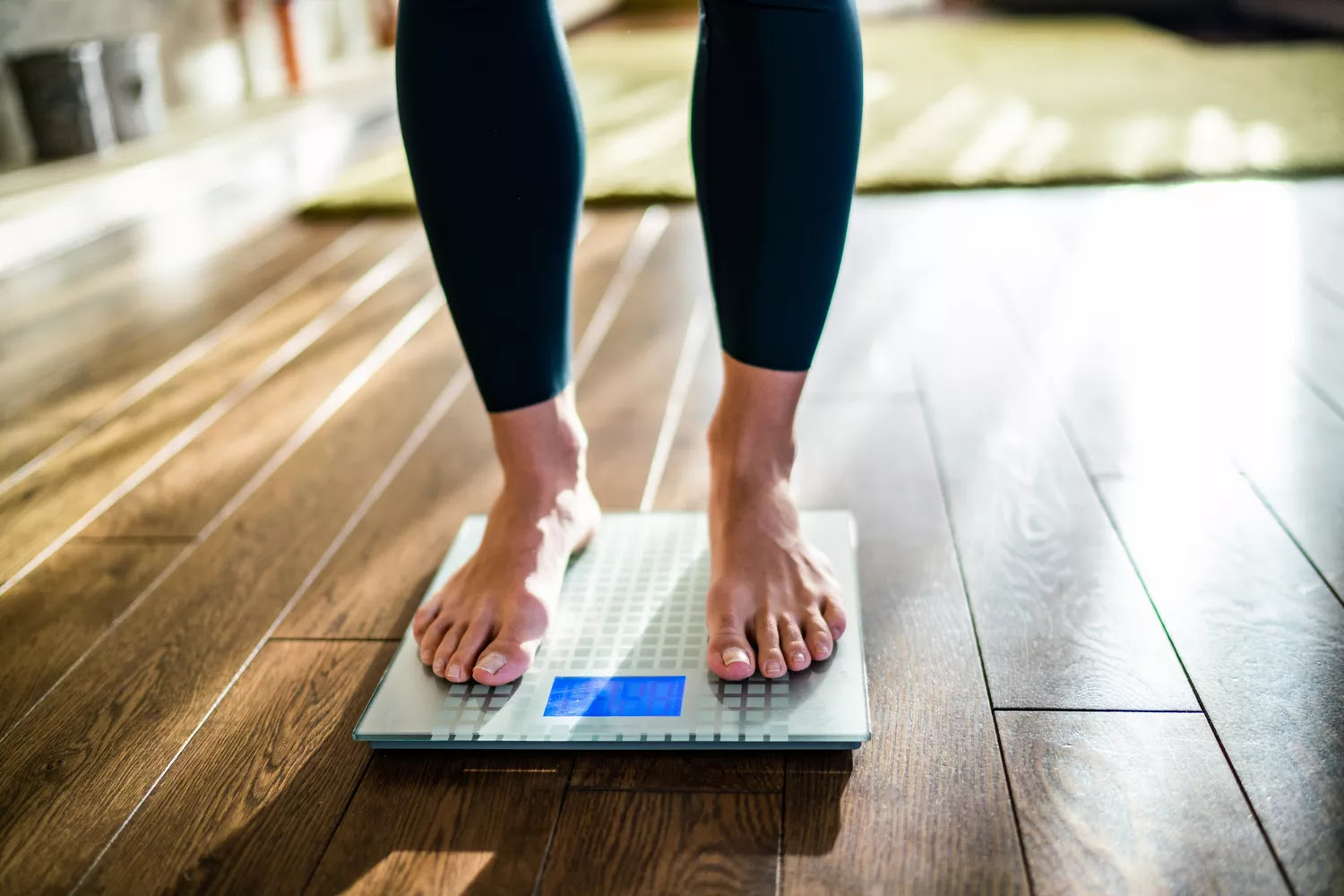 woman's feet standing on scale at home.