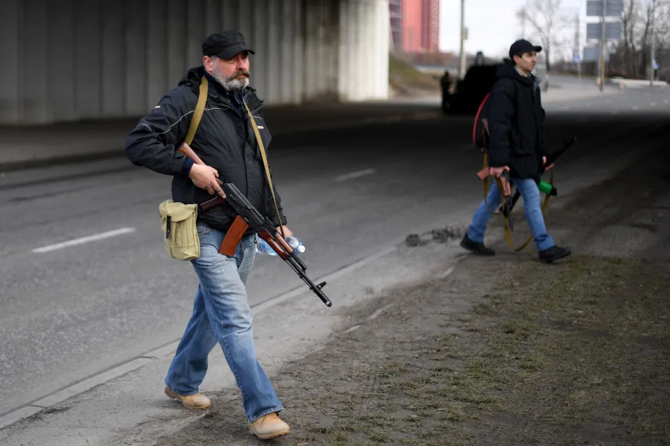 Volunteers, one holding an AK-47 rifle, in Kyiv.