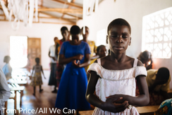 A young girl in a white dress prays at the front of a church in Malawi. Image: Tom Price/All We Can
