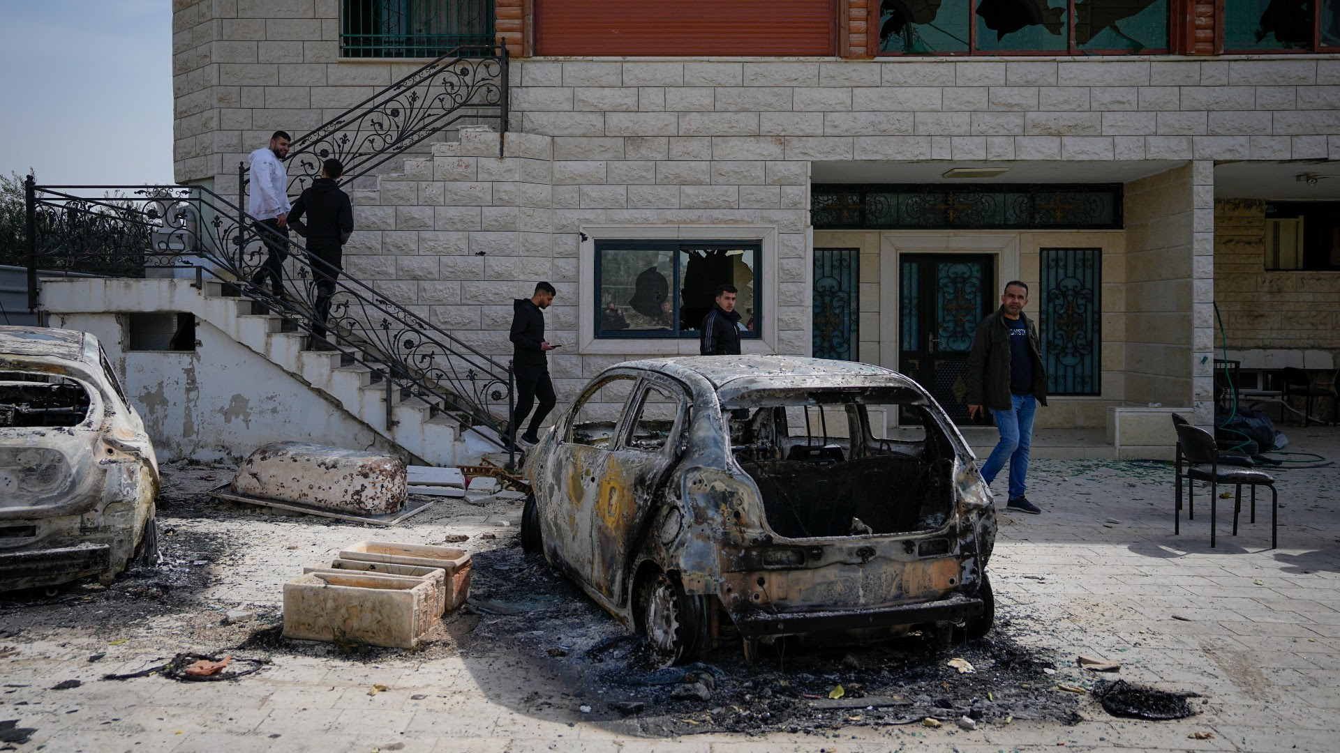 Palestinians inspect a damaged house and scorched cars in the town of Huwwara, near the West Bank city of Nablus, 27 February (AP) Palestinians inspect a damaged house and scorched cars in the town of Huwwara, near the West Bank city of Nablus, 27 February (AP)