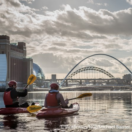 Two people kayaking on River Tyne with views of bridges