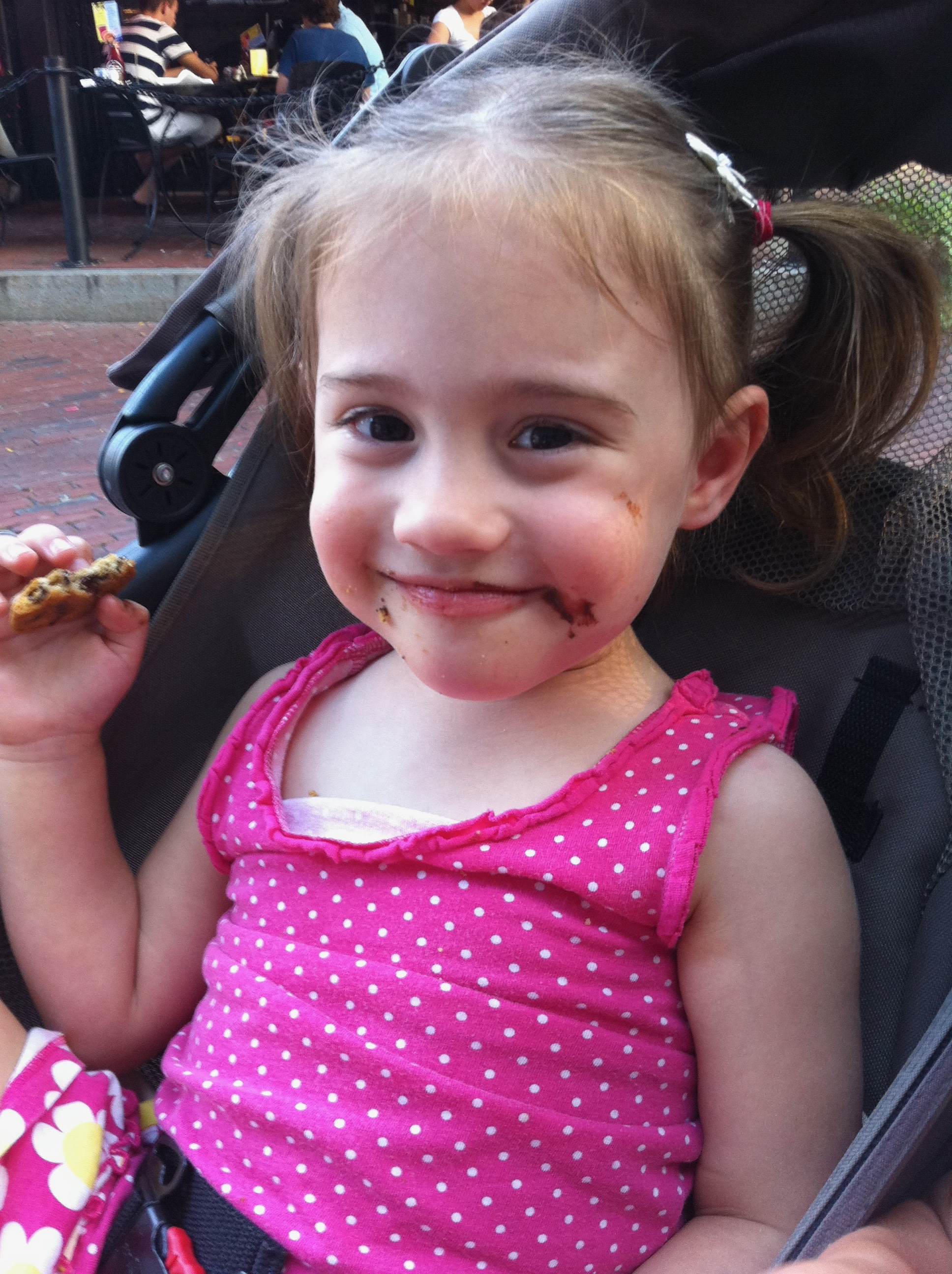 young girl in stroller eating a cookie