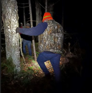 Hunter making their way out of the woods at night with help of rangers