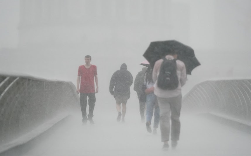 People with umbrellas walking in the rain on Millennium Bridge. Credit: Victoria Jones/PA