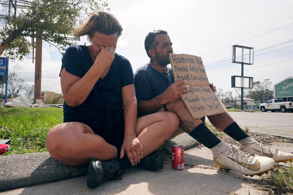 A homeless couple with a sign asking for help after Hurricane Ida in Homa.