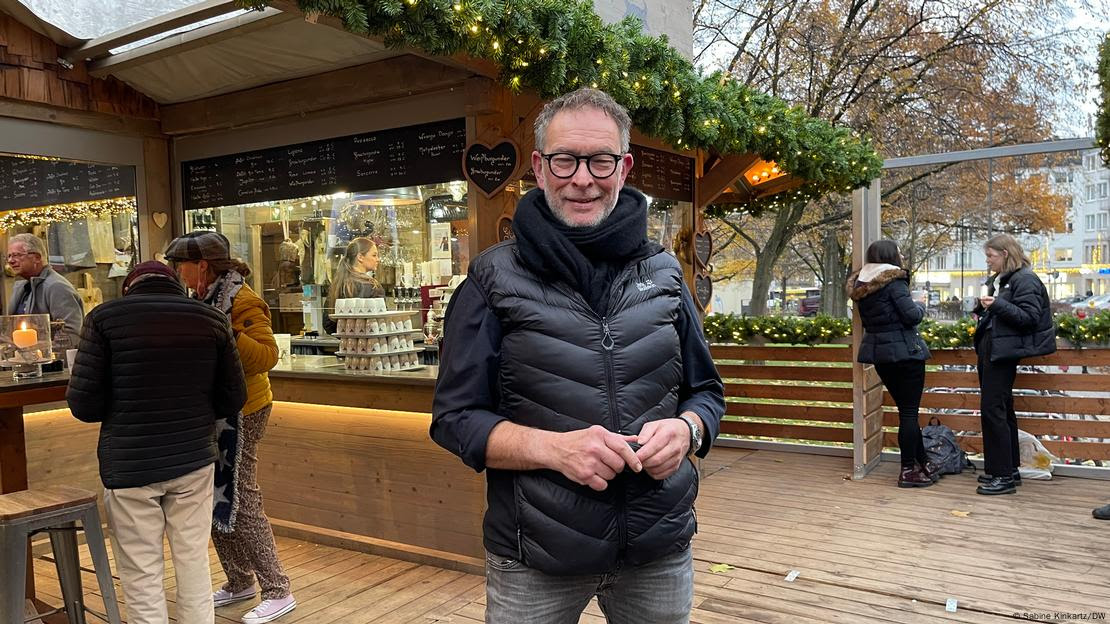 Foto mostra Rolf Gerrards em frente a banca de Natal.