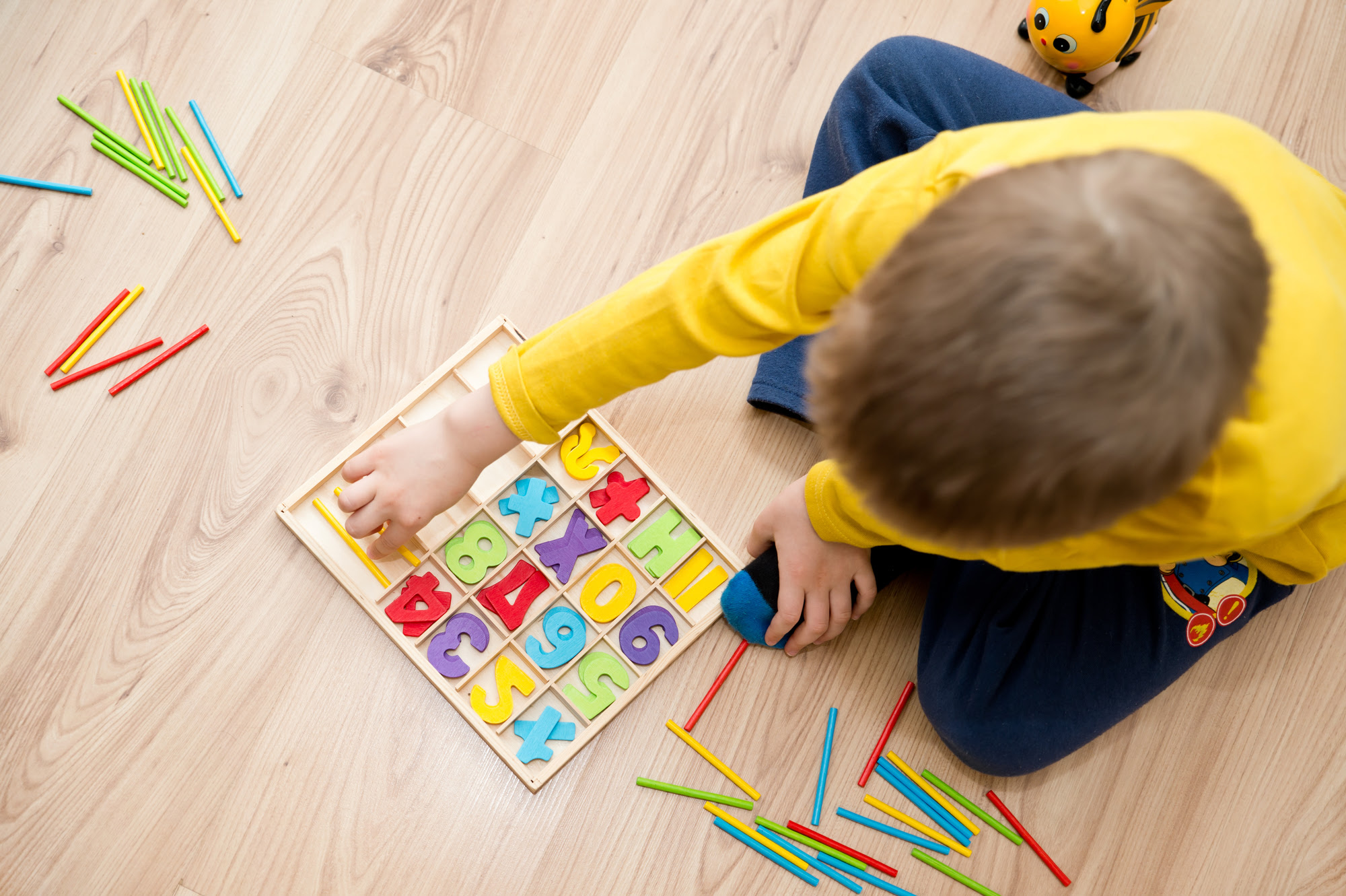 A little boy playing with a colorful counting number set on the floor.