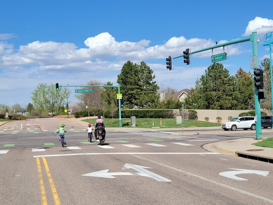 One adult and two children cross on bikes at the intersection of Rock Creek Parkway and Indiana Street in Superior