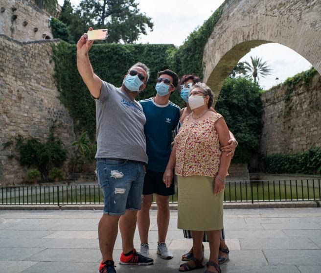 Varios turistas se hacen una foto junto a los Jardines de S'Hort del Rei de Palma de Mallorca durante el primer día de uso obligatorio de la mascarilla en Baleares por el Covid-19, en Palma de Mallorca, Islas Baleares (España) a 13 de julio de 2020.