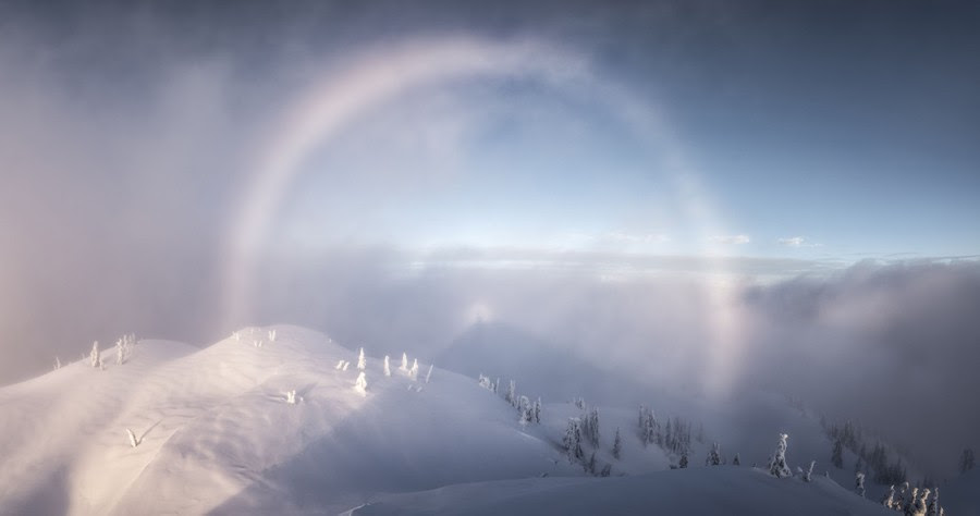 A view from a mountaintop, with the sun's rays forming a halo in the clouds.
