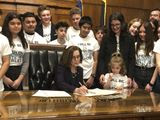 Oregon Gov. Kate Brown signs an executive order on Tuesday, March 10, 2020, ordering the state to lower greenhouse gas emissions, as students look on in Salem, Ore. In an end run around Republican legislators, Oregon&#39;s Democratic governor ordered the state on Tuesday to lower greenhouse gas emissions, directing a state agency to set and enforce caps on pollution from industry and transportation fuels. (AP Photo/Andrew Selsky)