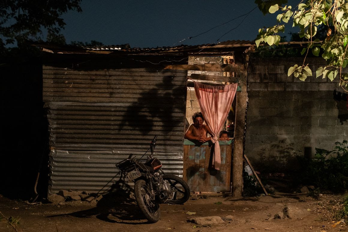 A family looks out from their home in the impoverished neighborhood of San Pedro Sula.