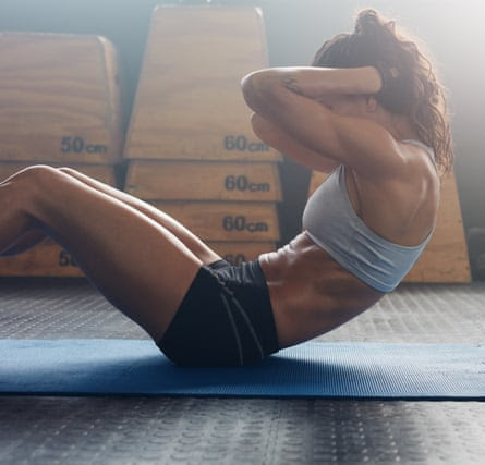 Muscular young woman does sit-ups.