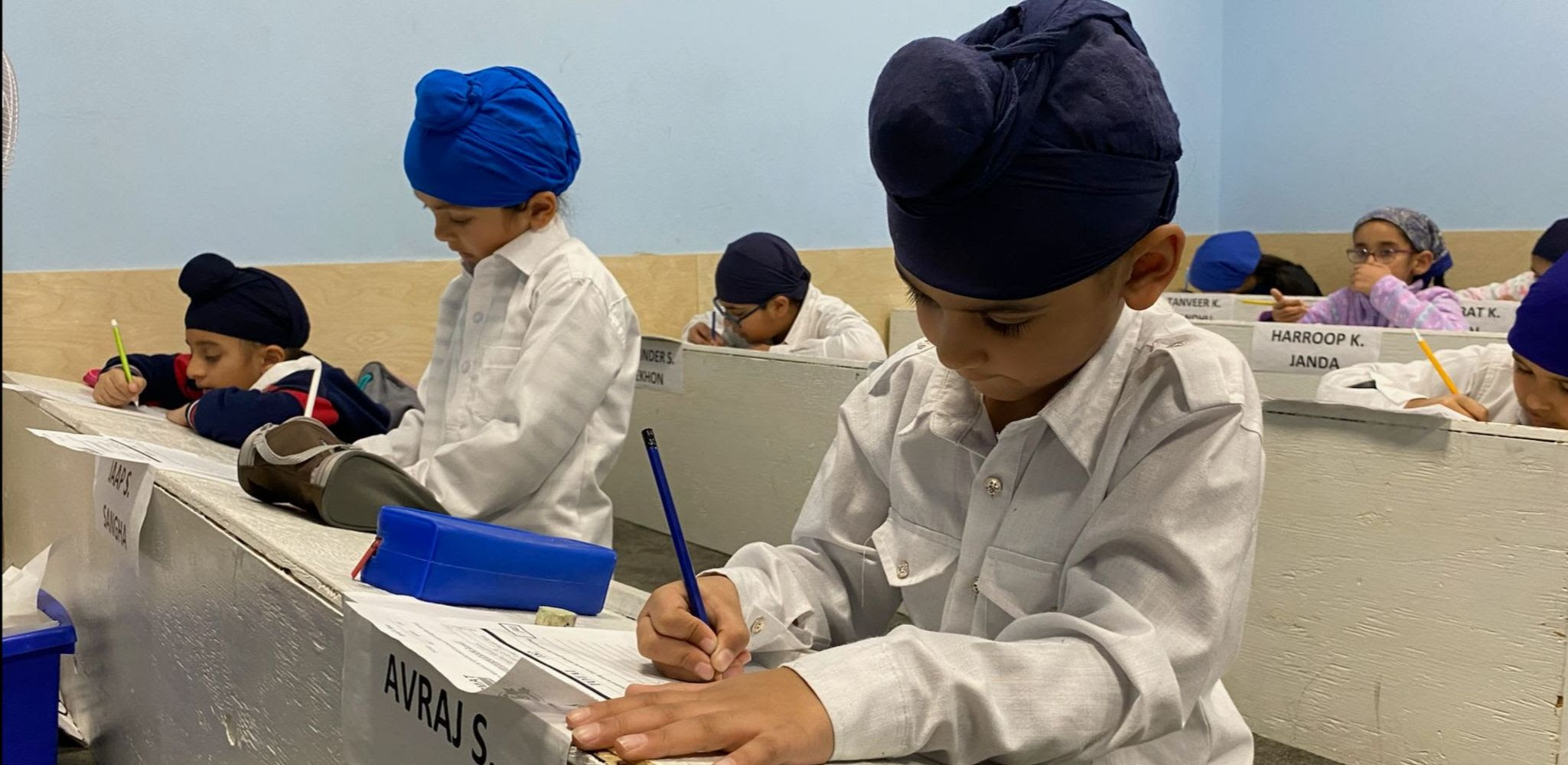 a group of children in a classroom writing on paper