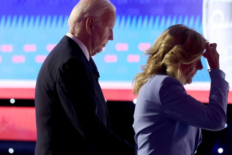 Jill Biden walks slightly in front of Joe Biden as they exit the debate stage. Both are gazing down and neither is smiling.