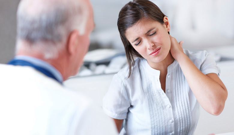 Woman grabbing her neck in pain while talking with a doctor