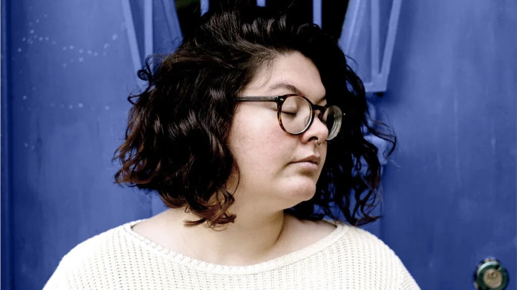 Female against a dark blue background, looking away from the camera