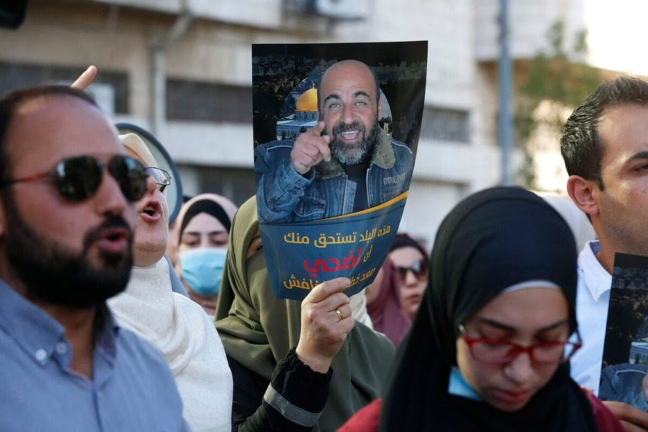 Palestinians hold posters depicting human rights activist Nizar Banat during a protest triggered by the violent arrest and death in custody of Banat, in his hometown of Hebron in the occupied West Bank, on June 27, 2021 [MOSAB SHAWER/AFP via Getty Images]