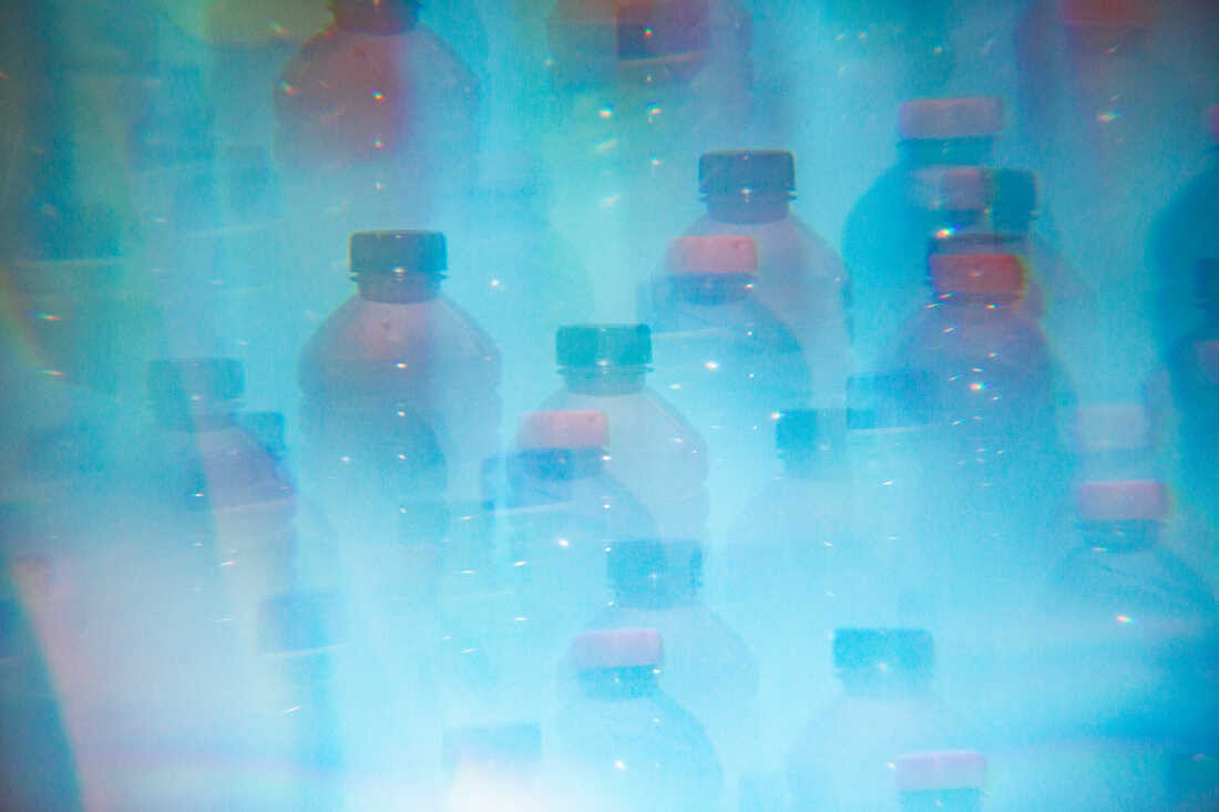 Various colorful sports drinks photographed through a prism against a blue backdrop.